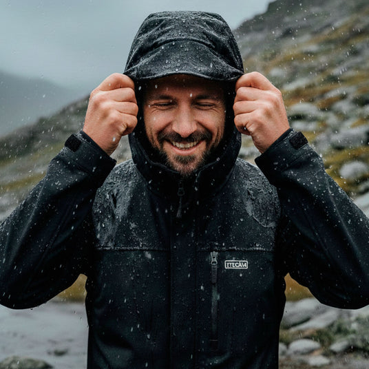 hombre usando chaqueta impermeable técnica en montaña bajo la lluvia